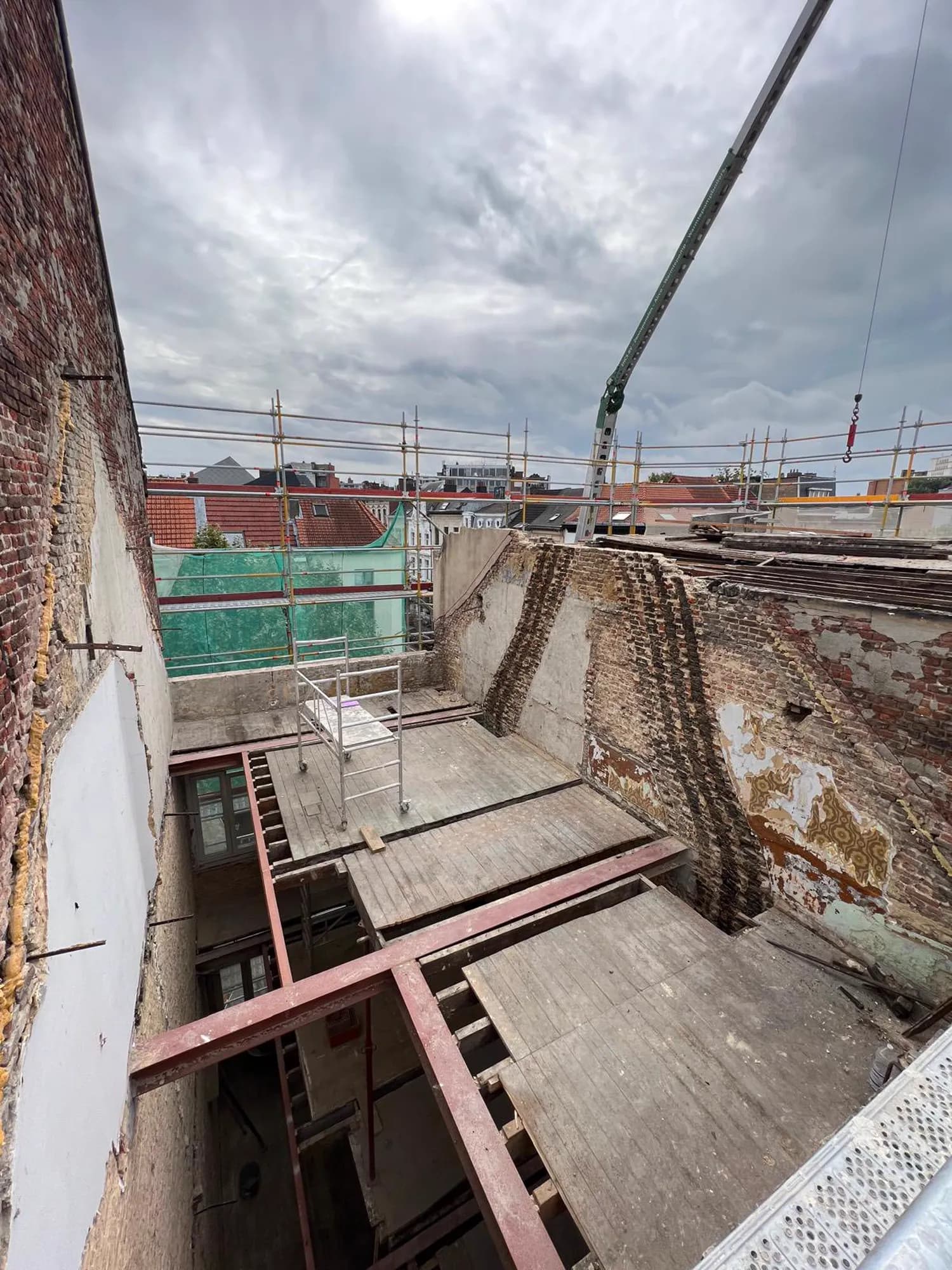 Een opengelegde woning in Antwerpen: gestripte bakstenen muren, nieuwe stalen liggers en een open dak.